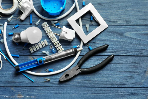 Elektrikerwerkzeug, Kabel, Steckverbindungen und Leuchtmittel auf einer Arbeitsfläche symbolisieren die technische Vorbereitung für professionelle Lichtplanung Gewerberaum.